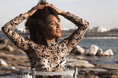 Portrait of young woman standing against sea