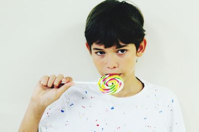 Portrait of boy holding ice cream against white background
