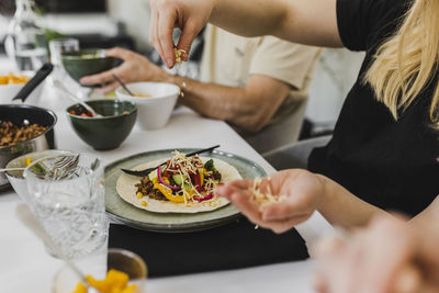 Woman adding various toppings to tortilla