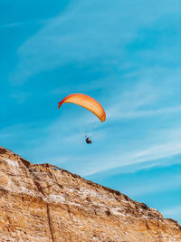 Low angle view of person paragliding against sky