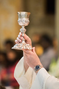 Cropped hands of priest holding chalice in church