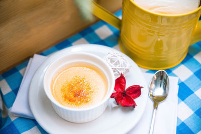 A portion of delicate creme brulee in ramekin on the table on a checkered napkin