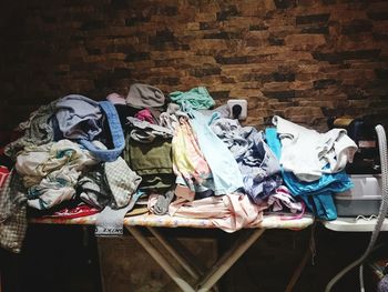 Laundry heap on table against stone wall