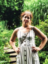 Portrait of a young woman standing against plants