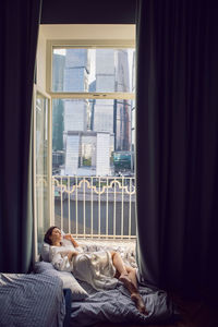 Low section of woman relaxing on bed at home