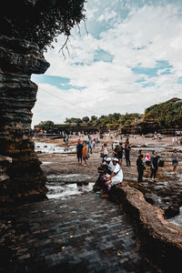 People enjoying at shore against sky