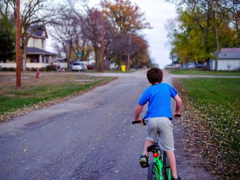 Rear view of boy cycling on road