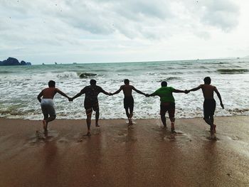 People running at beach against sky