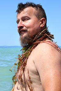 Shirtless man with plants in sea against clear sky