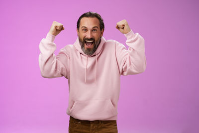 Portrait of man standing against pink background