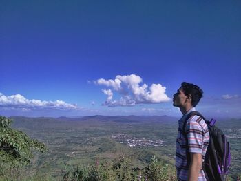 Young man looking at mountain against sky