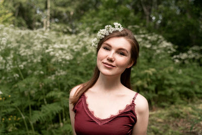 Portrait of smiling young woman standing against plants in park