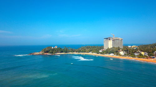 Scenic view of sea and buildings against blue sky in the southern coast of sri lanka