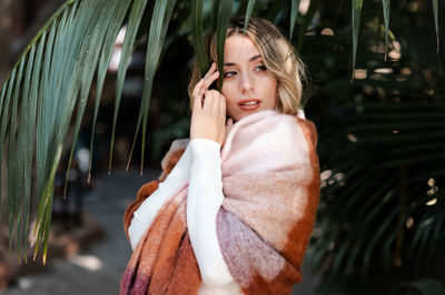 Portrait of young woman standing against plants