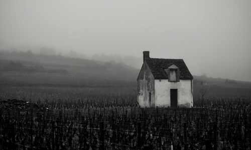 Old house on field against sky during foggy weather