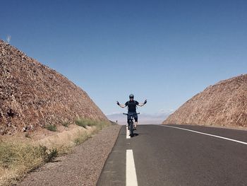 Rear view of man riding motorcycle on road against sky