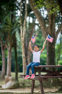 Full length of boy sitting on tree