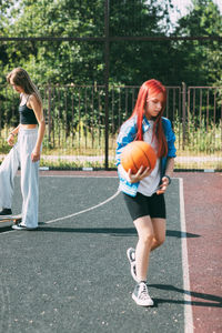 Teen girl with a skateboard on a sports field, blurred foreground