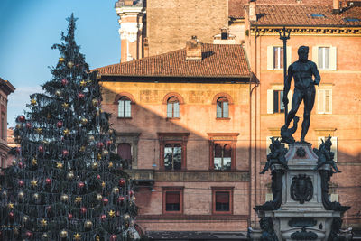 Statue and christmas tree against building