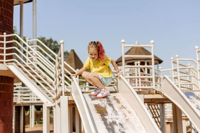 Cute little girl rides down a slide on the playground