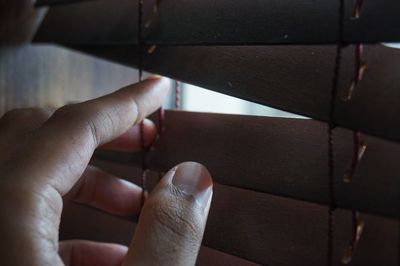 Cropped hand of person holding window blinds