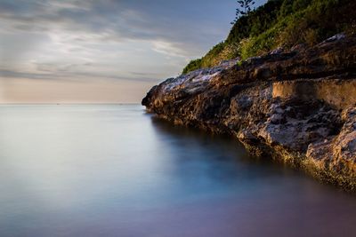 Rock formation in sea against sky