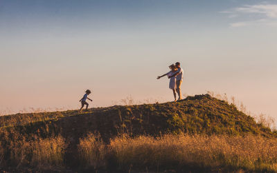 People standing on land against sky during sunset