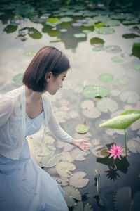 Young woman looking down while standing on plant