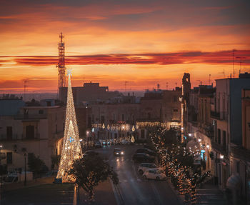 Illuminated city against sky at sunset