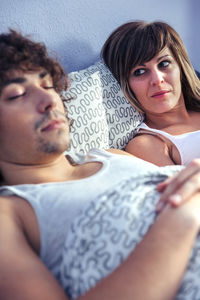 Thoughtful woman with boyfriend lying down on bed