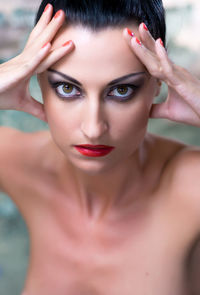 Close-up portrait of confident shirtless woman with make-up