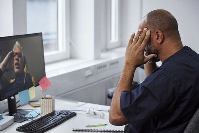Male doctor having online consultation with senior patient