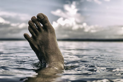 Low section of man swimming in sea against sky