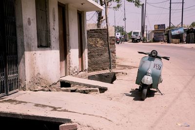 Scooter parked by building on sunny day