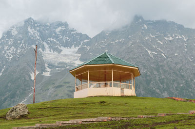Gazebo on snowcapped mountain against sky
