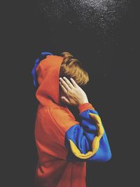 Rear view of boy standing against black background