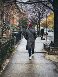 Rear view of person walking on footpath in winter