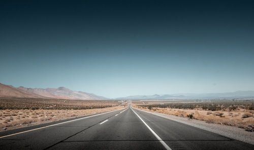 Empty road along landscape against clear sky