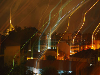 Illuminated street amidst buildings against sky at night