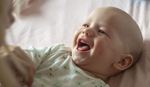 Closeup portrait of cute baby boy. a 3-5 month old boy laughs at his mum when lying in bed