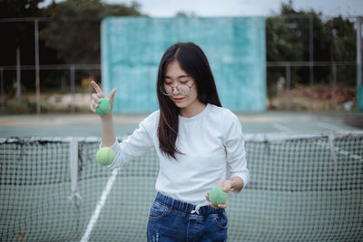 Young woman playing with balls at tennis court