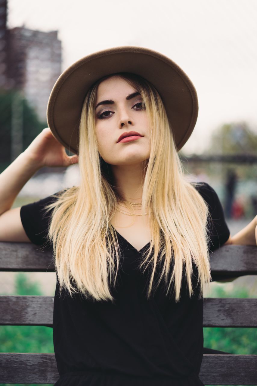 hat, real people, one person, young adult, lifestyles, focus on foreground, young women, portrait, front view, looking at camera, fashion, outdoors, leisure activity, beautiful woman, day, standing, blond hair, close-up