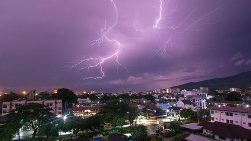 Lightning over illuminated buildings in city at night