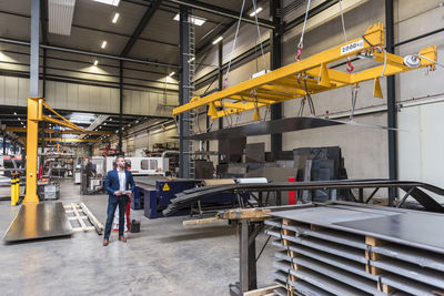 Businessman with tablet standing on factory shop floor