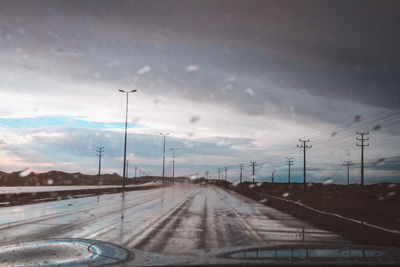 Road against sky seen through windshield during rainy season