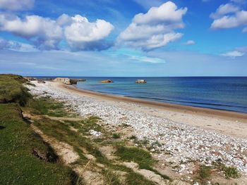 Scenic view of beach against cloudy sky