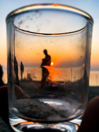 Close-up of beer glass against sky during sunset