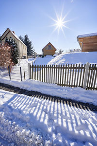 Snow covered houses by building against sky