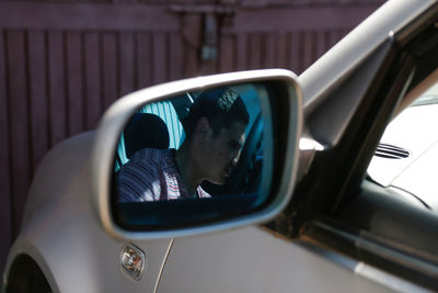 Serious successful caucasian young man sitting in car. reflection in mirror. silver grey gray car. 