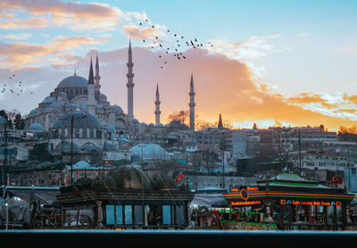 Buildings in city against sky during sunset